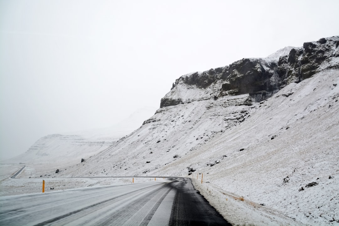 gray asphalt road between snow covered mountains during daytime