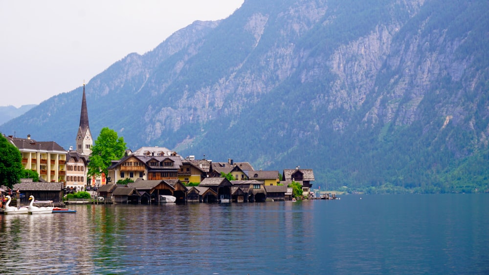brown wooden houses on water near mountain during daytime