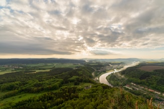 A panoramic view of a winding river cutting through lush green valleys, captured from a high vantage point.