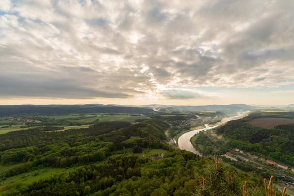 A panoramic view of a winding river cutting through lush green valleys, captured from a high vantage point.