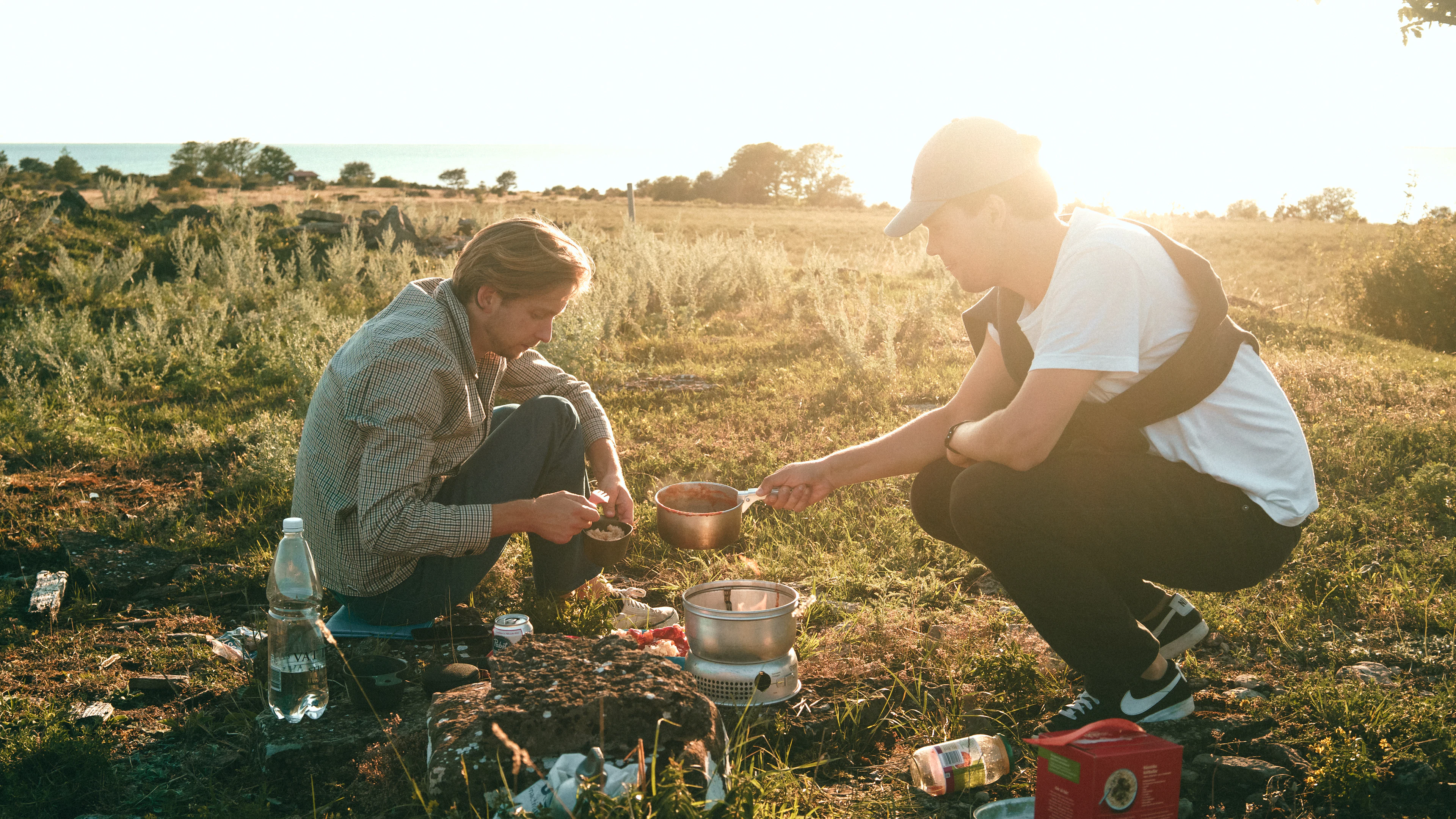 Two people cooking at a campsite in the evening sun