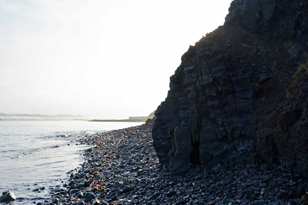 gray rocky mountain near body of water during daytime