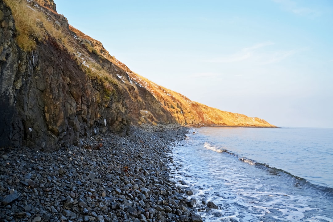 brown rocky mountain beside body of water during daytime