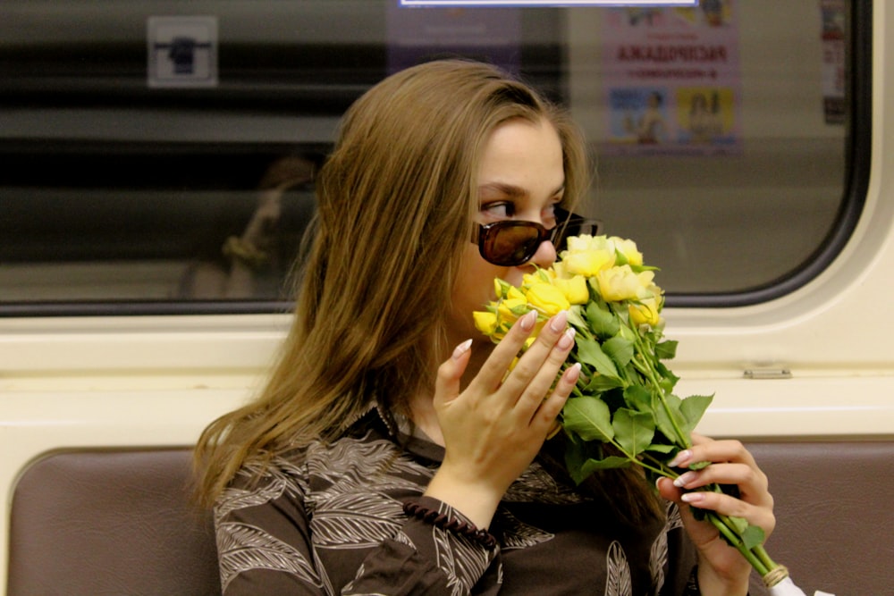 woman in black leather jacket holding yellow flower