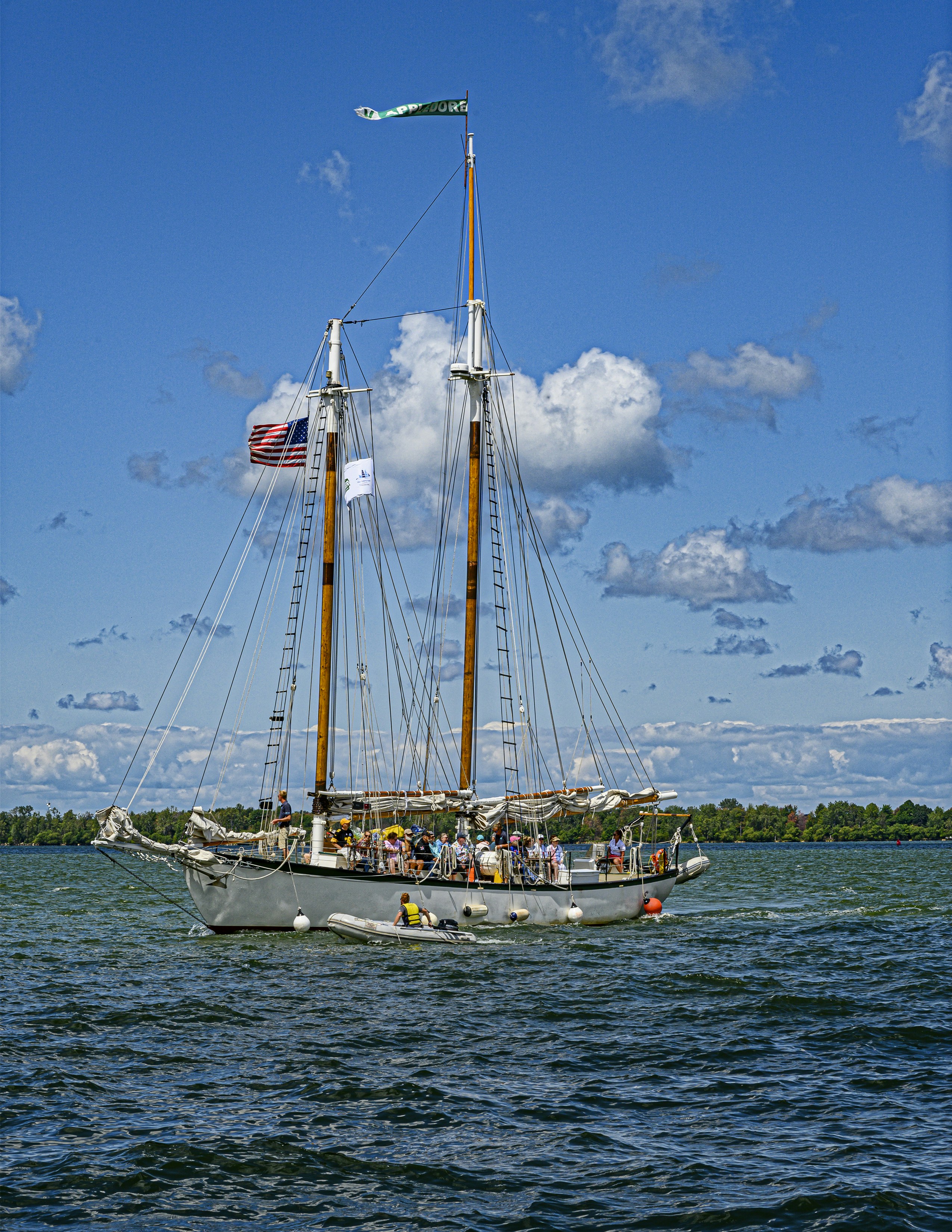 昼間の青空の下、海上に浮かぶ白い帆船