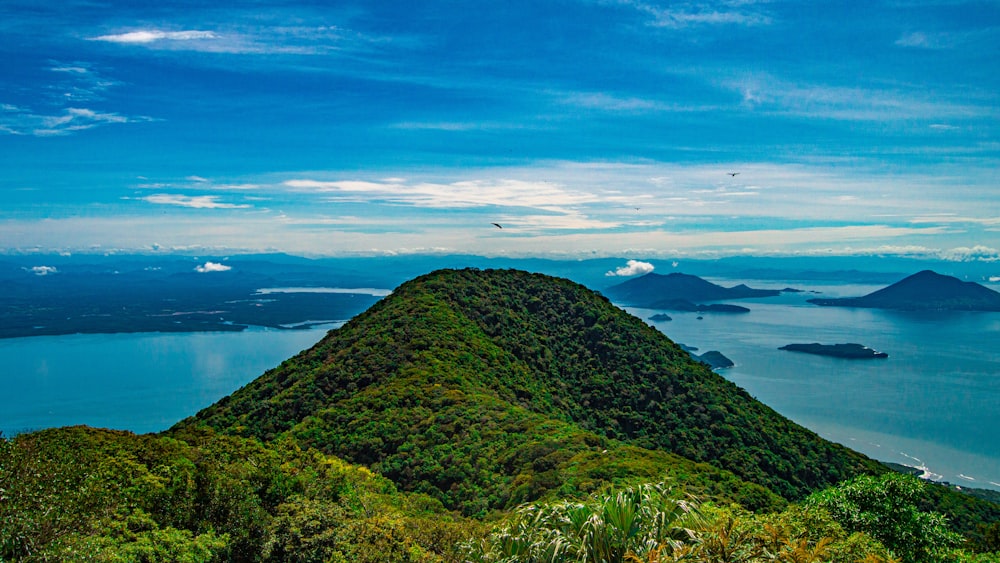 green grass covered mountain near body of water during daytime