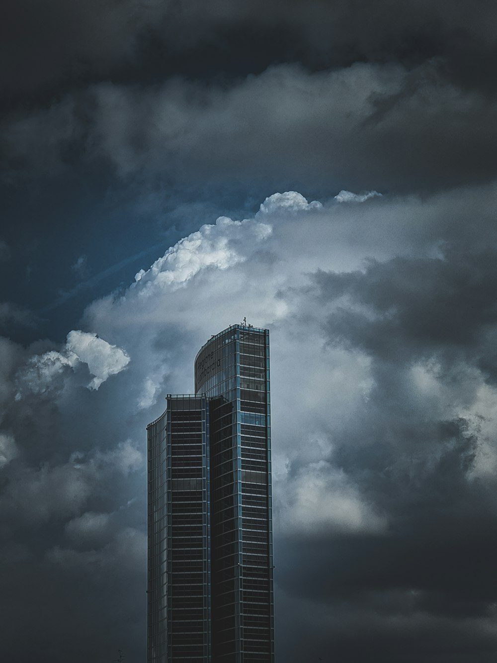 grayscale photo of high rise building under cloudy sky