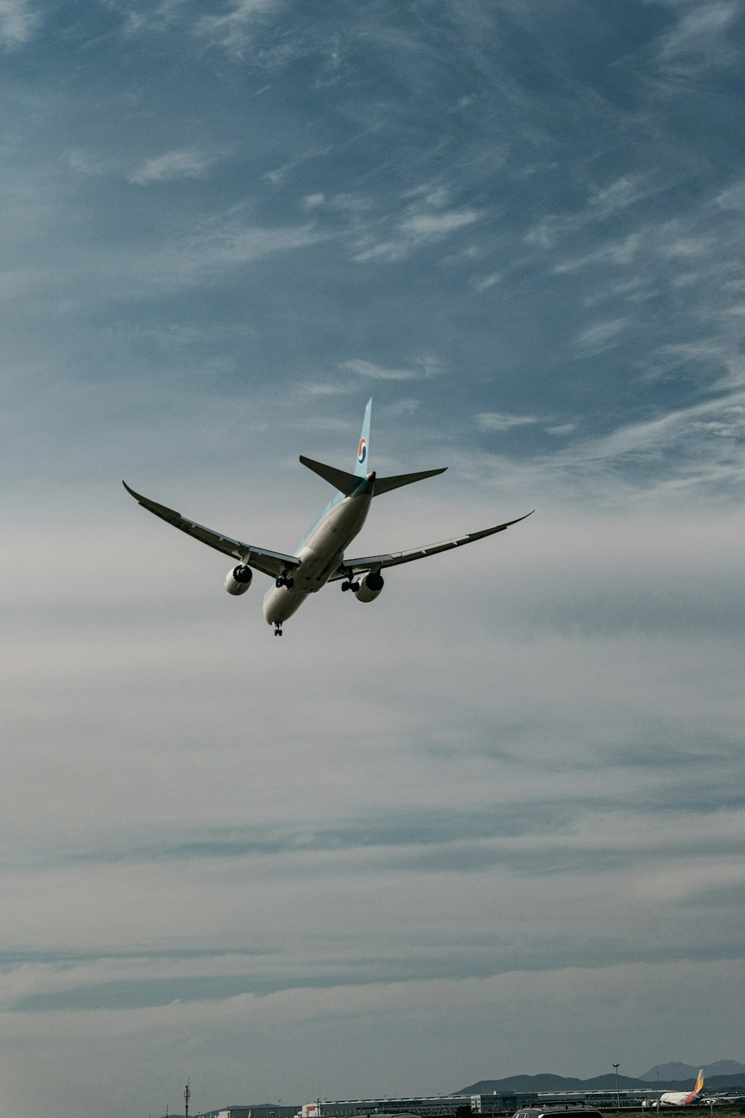 white airplane flying under blue sky during daytime