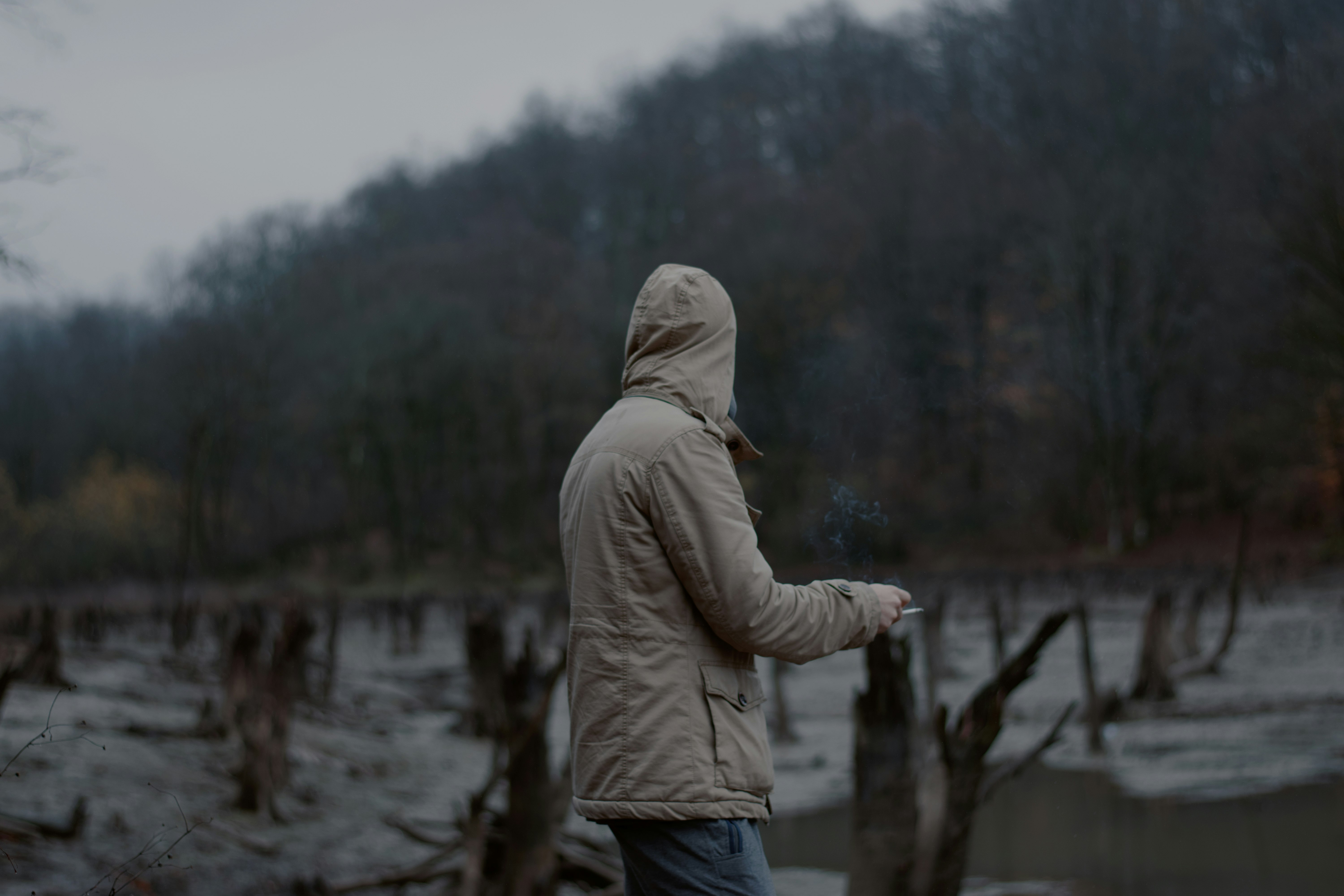 man in gray hoodie standing on brown wooden dock during daytime