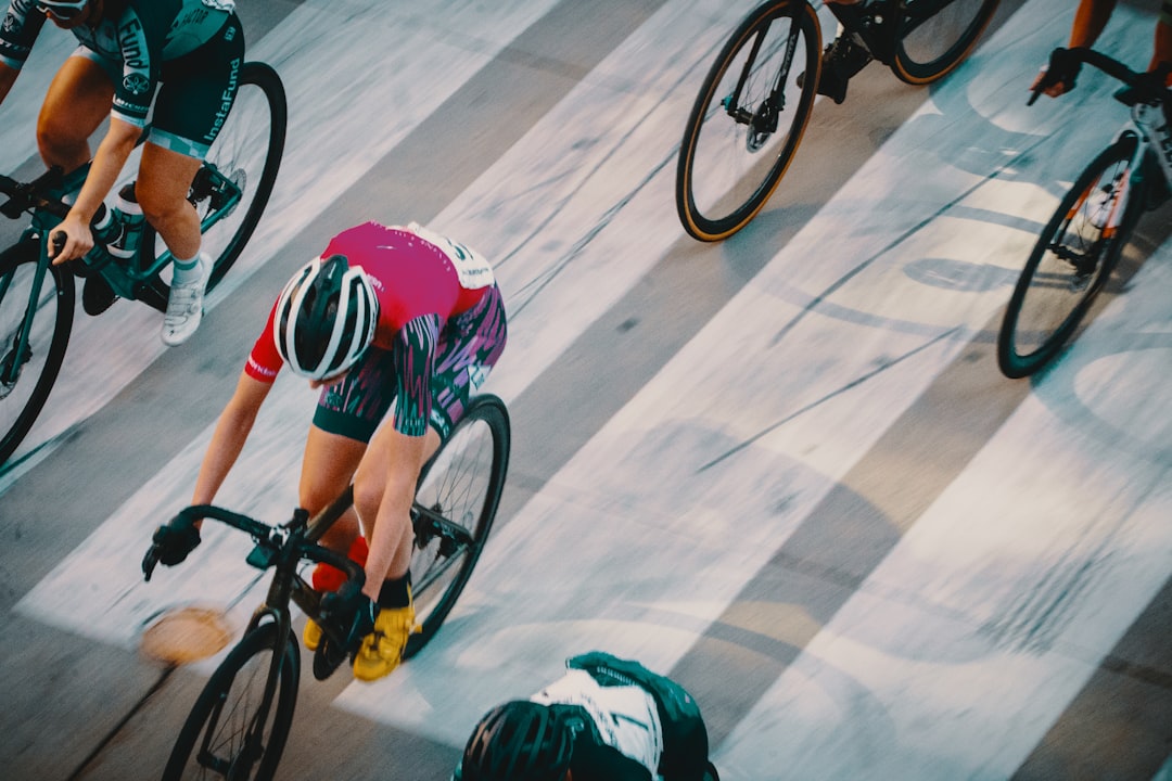 person in green and black shorts riding on black and red bicycle