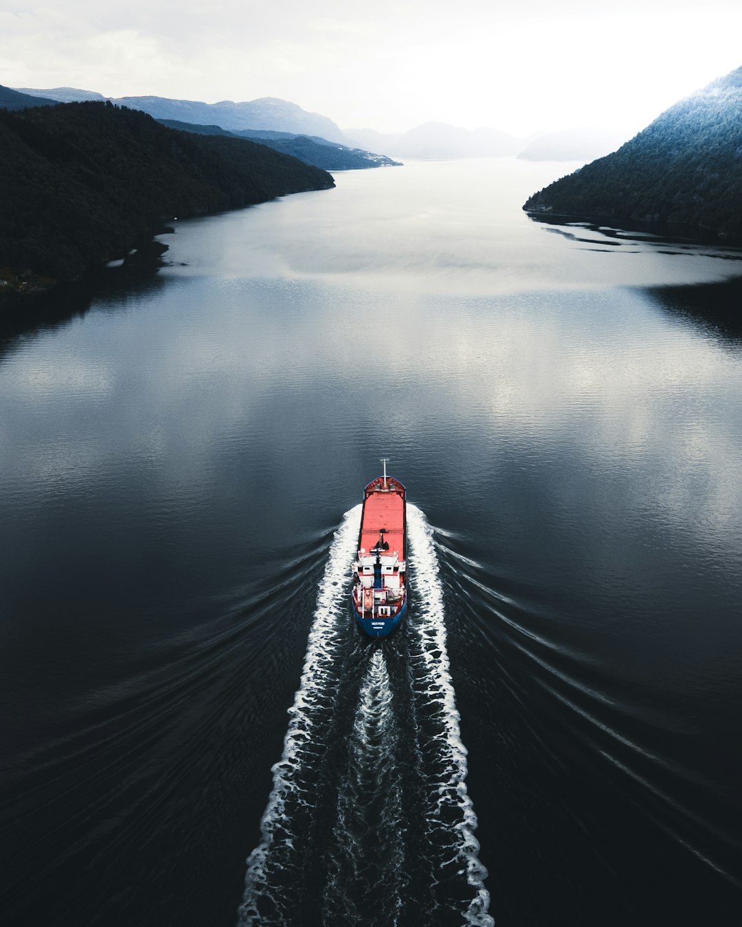 person in black jacket and black pants standing on boat on lake during daytime