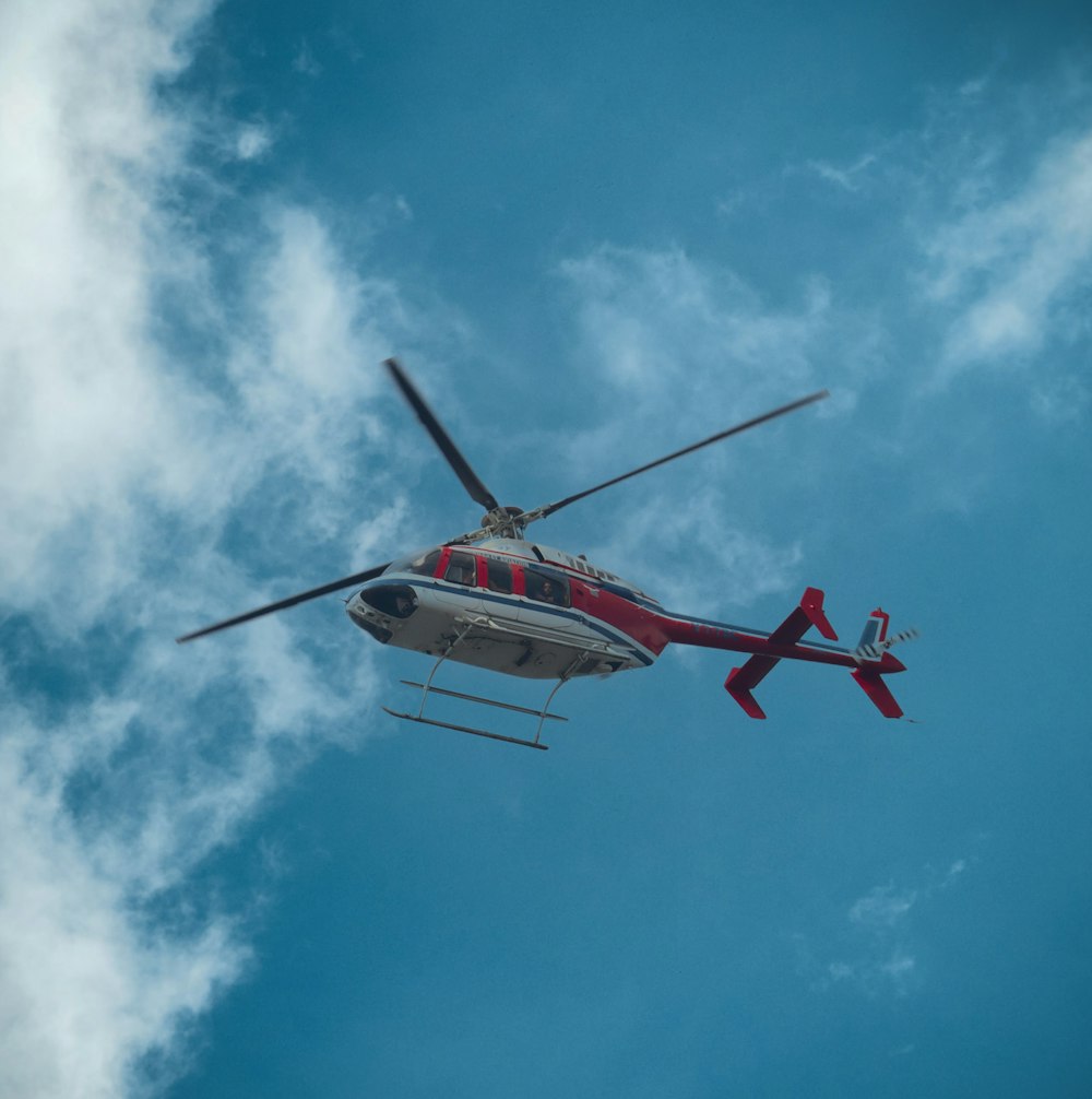 red and white helicopter flying in the sky