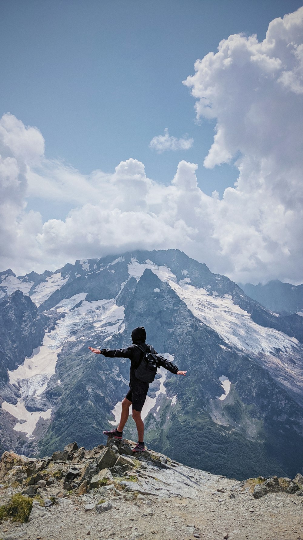 man in black jacket and pants jumping on snow covered mountain during daytime