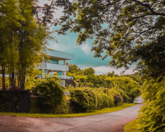 An outdoor shot of a modern data centre building framed by tall trees and natural brown stone accents.