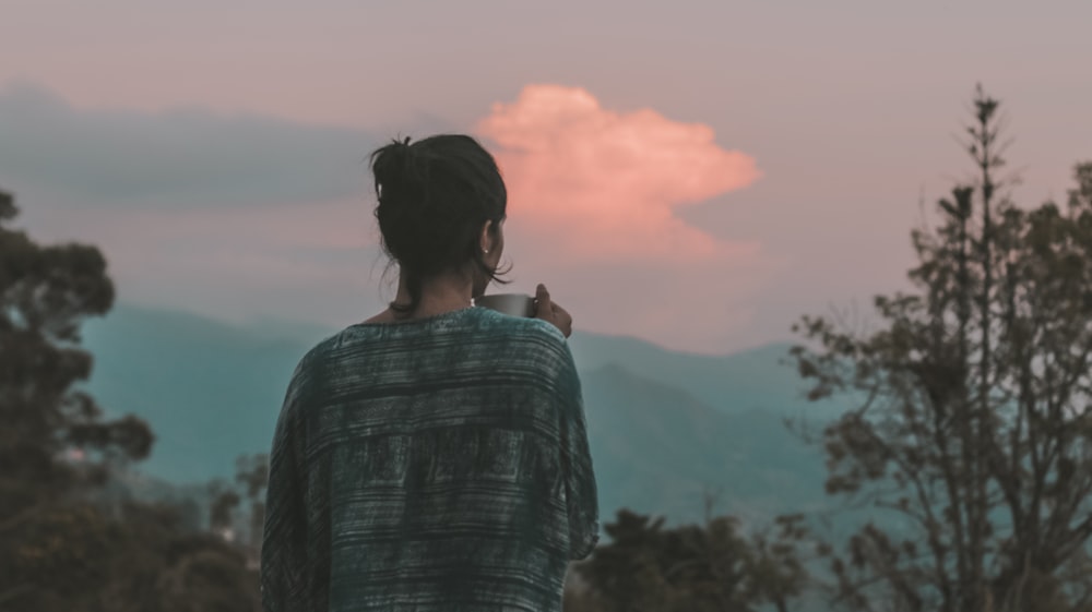 woman in black and white stripe shirt standing on mountain during daytime