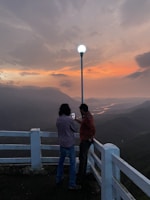 A scenic photo of a guide and traveler enjoying a sunset viewpoint together.
