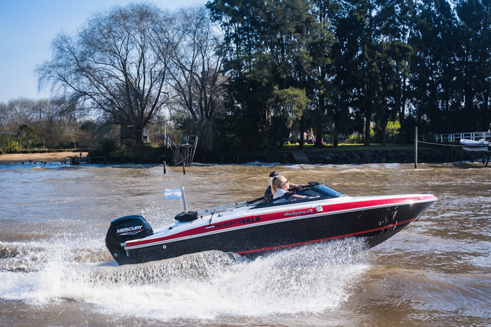 homem que monta barco vermelho e branco na água durante o dia