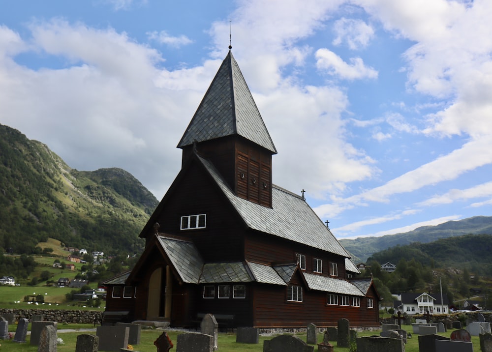 Maison en bois marron et noir près de la montagne verte sous les nuages blancs pendant la journée