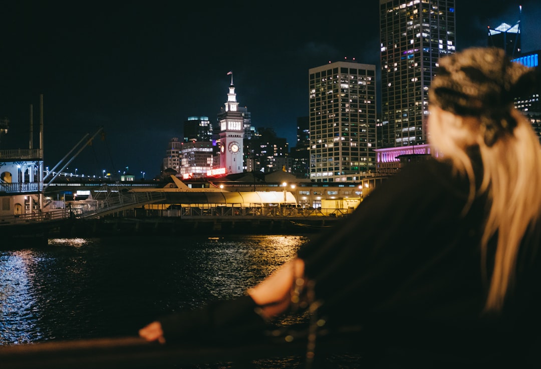 man in black jacket standing near body of water during night time