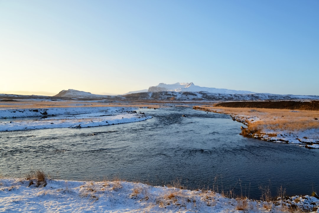 brown and white mountains near body of water under blue sky during daytime