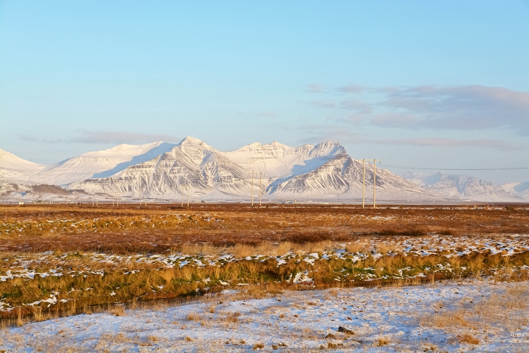 brown grass field near snow covered mountain during daytime