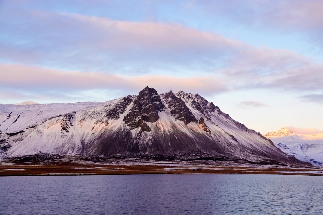 snow covered mountain near body of water during daytime