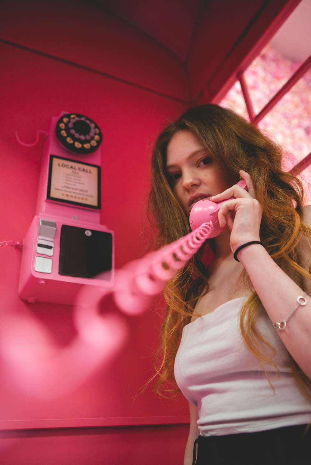 woman in white long sleeve shirt holding pink phone