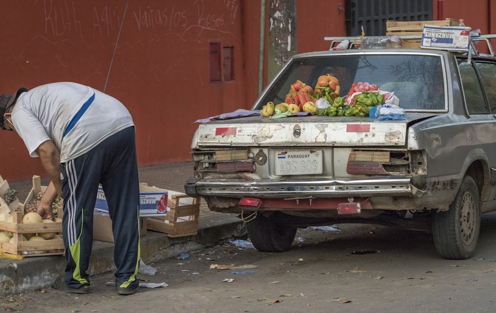 man in blue shirt standing beside red car