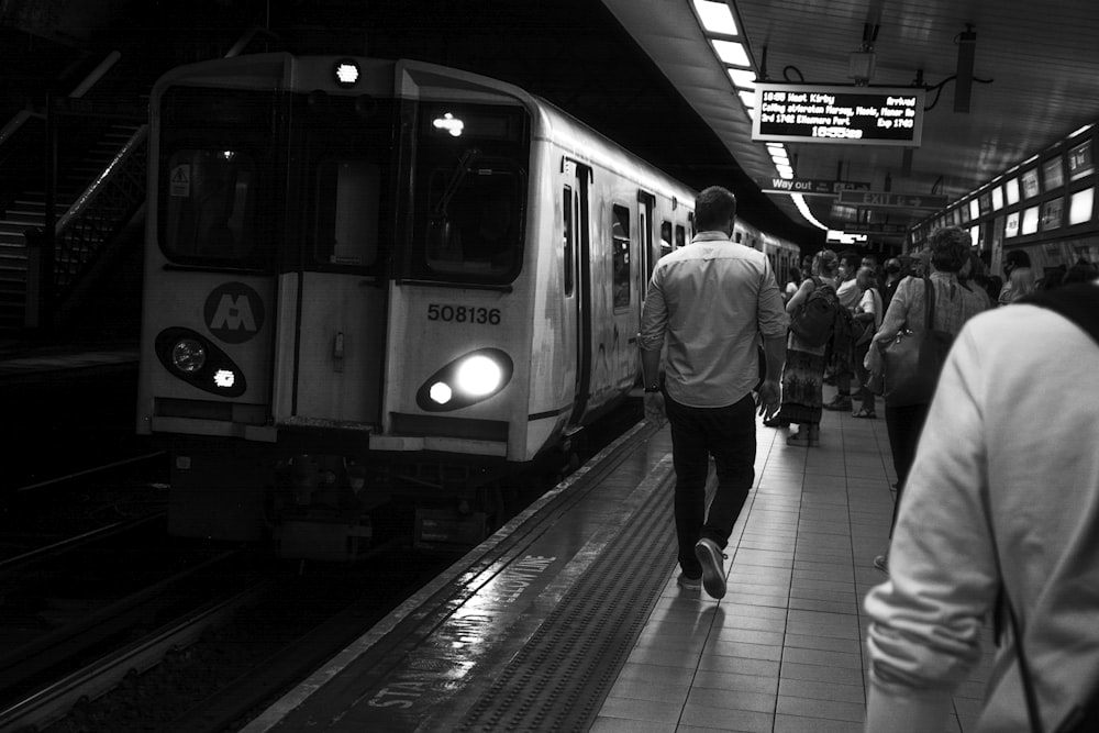 foto em tons de cinza de pessoas andando na estação de trem