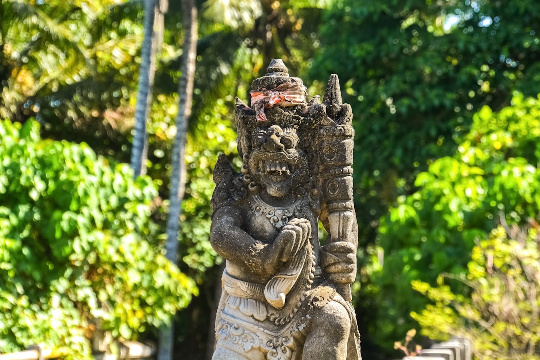 brown concrete statue near green trees during daytime