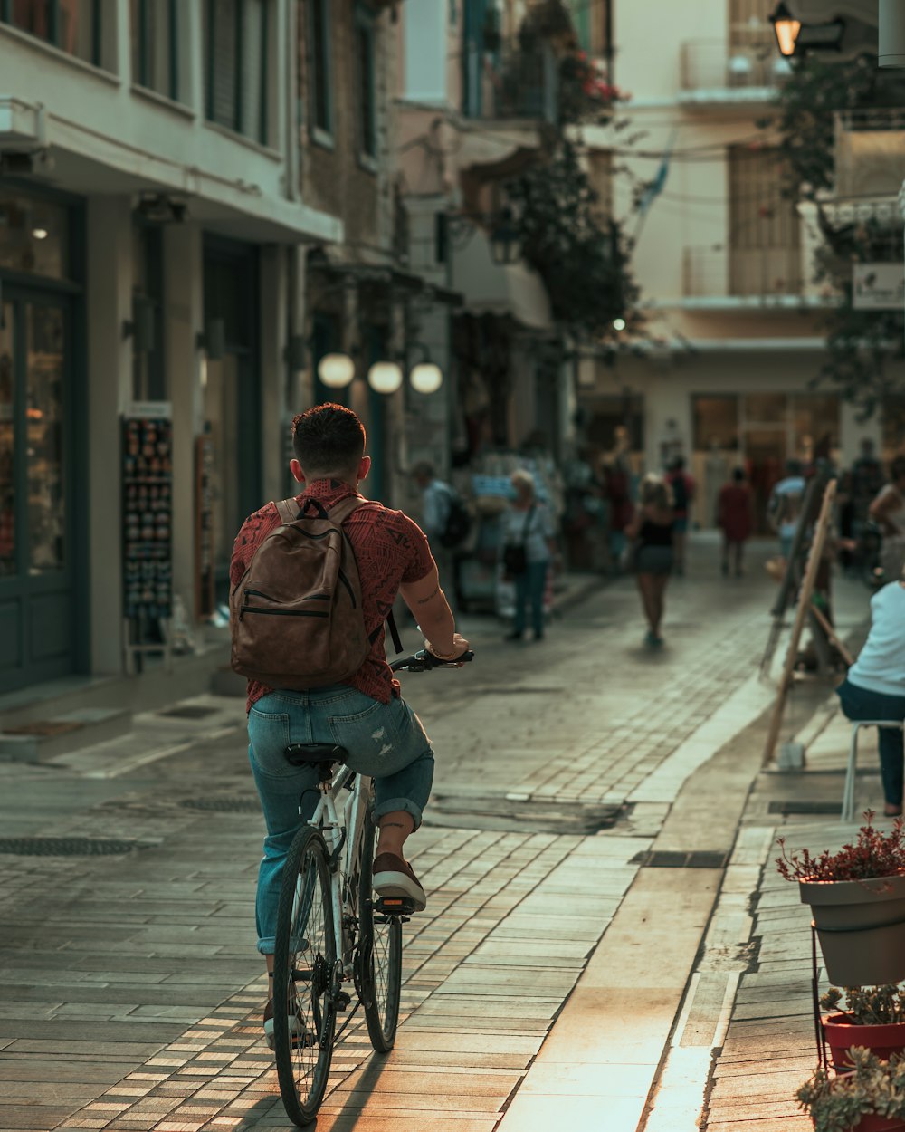 man in red jacket riding bicycle on street during daytime