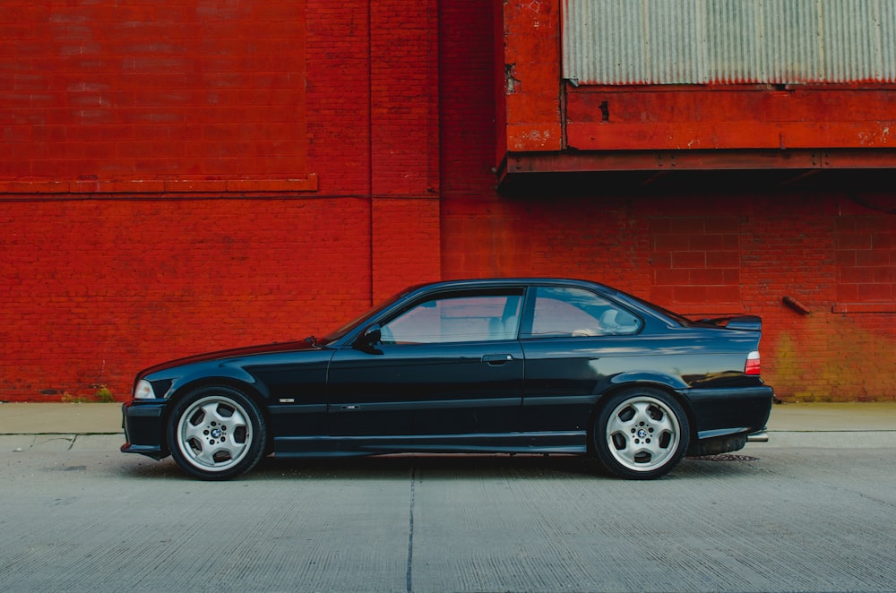 blue sedan parked beside red wall