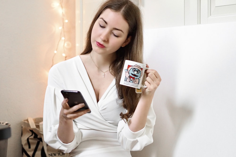 woman in white long sleeve shirt holding white and black box