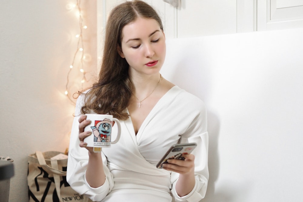 woman in white v neck long sleeve shirt holding white ceramic mug