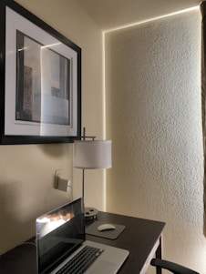 A sleek workspace featuring a minimalist desk with a high-end laptop, soft natural light casting shadows on deep midnight blue walls.