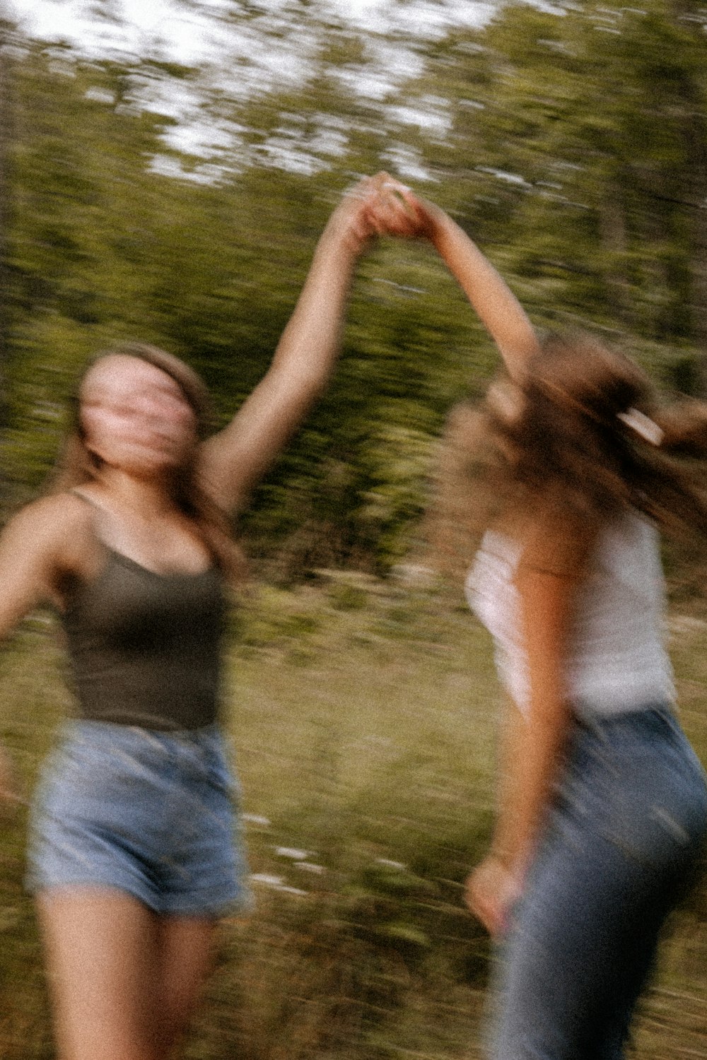 woman in gray tank top and blue denim jeans standing on green grass field during daytime