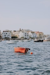 red boat on body of water near city buildings during daytime