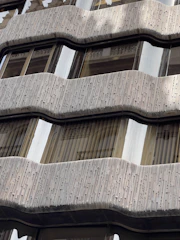 Close-up of a sleek glass windscreen protecting a balcony on a windy day.