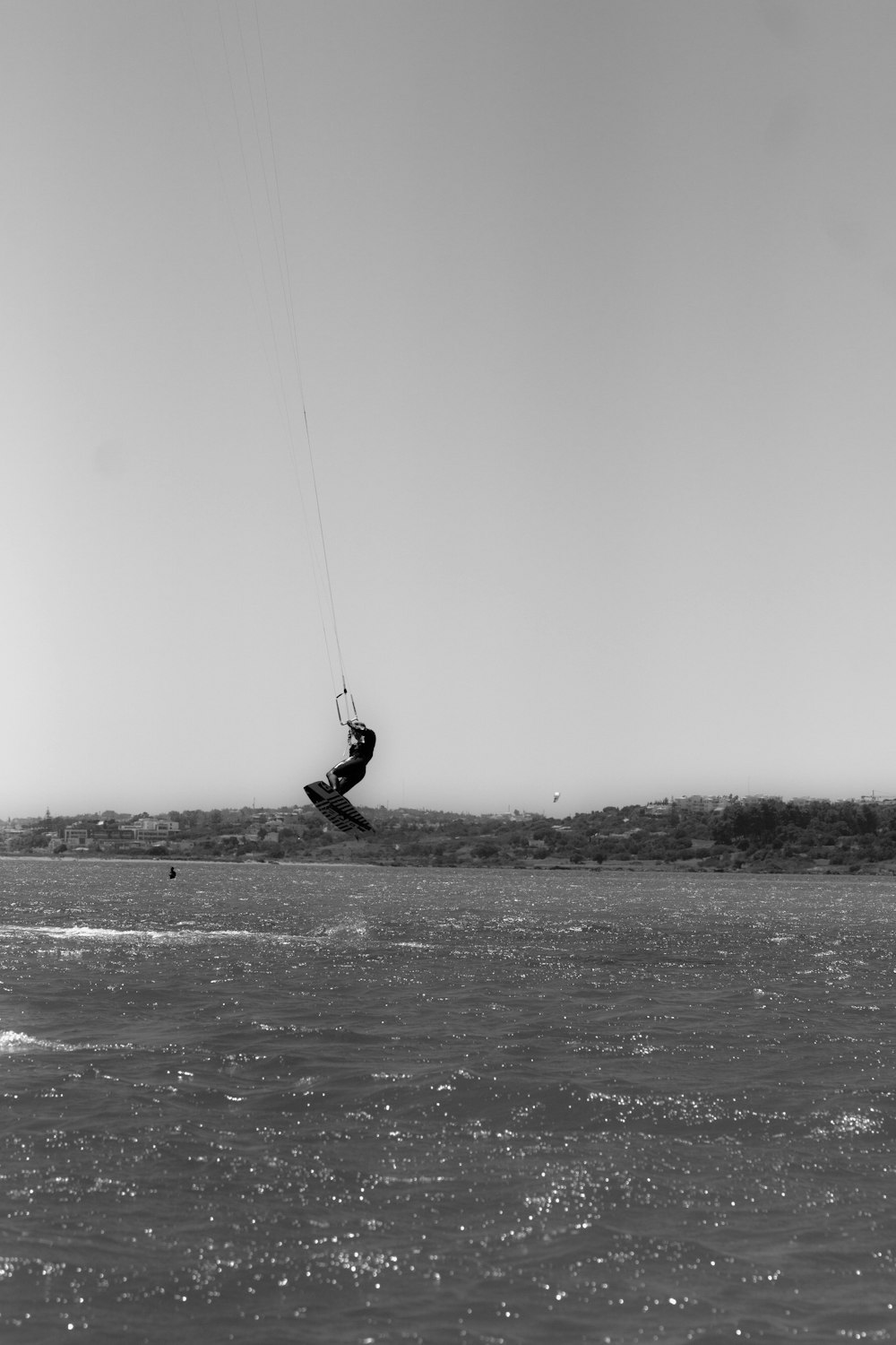 grayscale photo of person riding on swing over the sea
