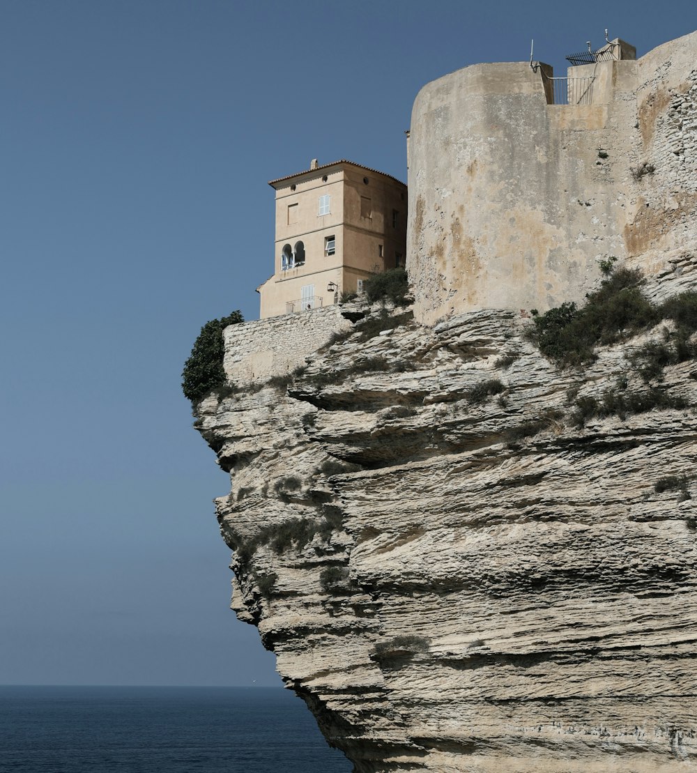 brown concrete building on cliff by the sea during daytime