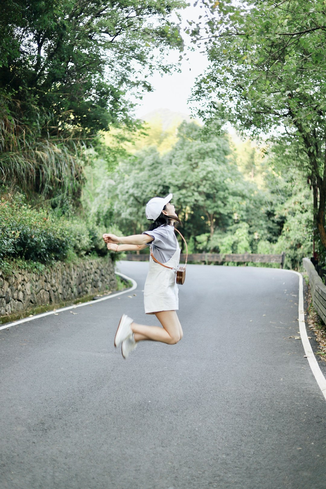 woman in white shirt and white shorts walking on the road during daytime