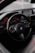 A sleek car interior featuring a BMW steering wheel with a sporty, high-tech design. The dashboard is sophisticated with illuminated red dials and a digital screen.