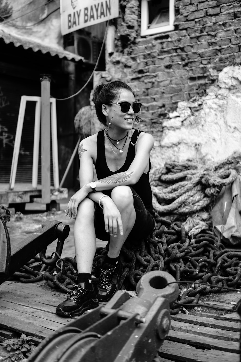 a black and white photo of a woman sitting on a dock