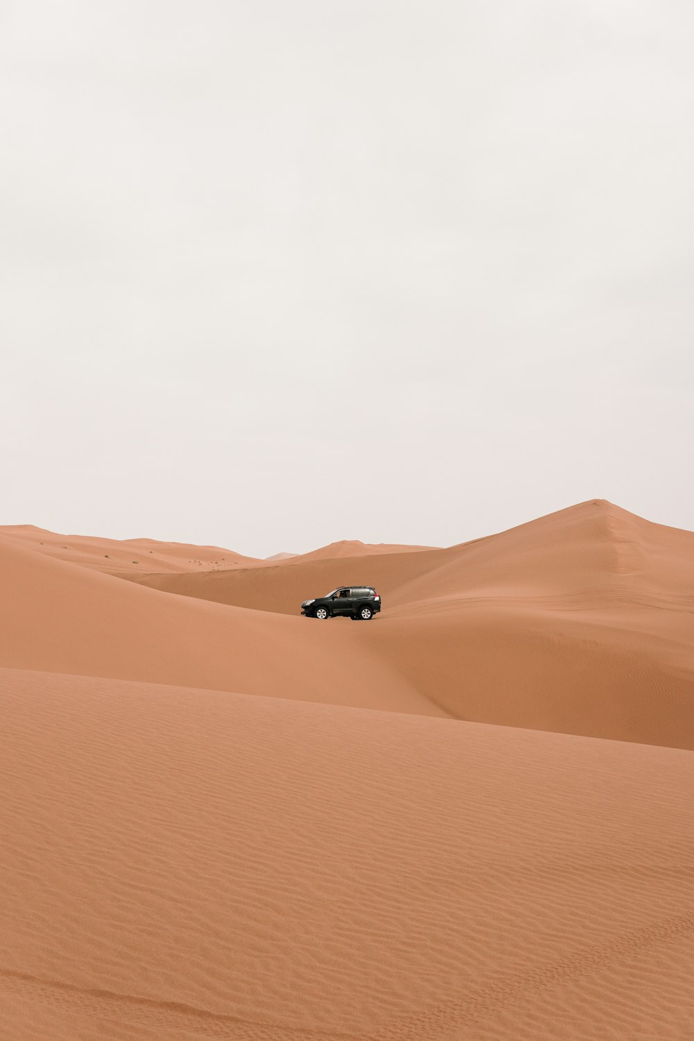 a car driving through the desert in the middle of the day