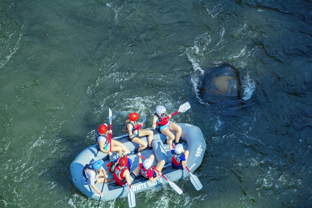 people in blue and red life vest riding on inflatable raft on water during daytime