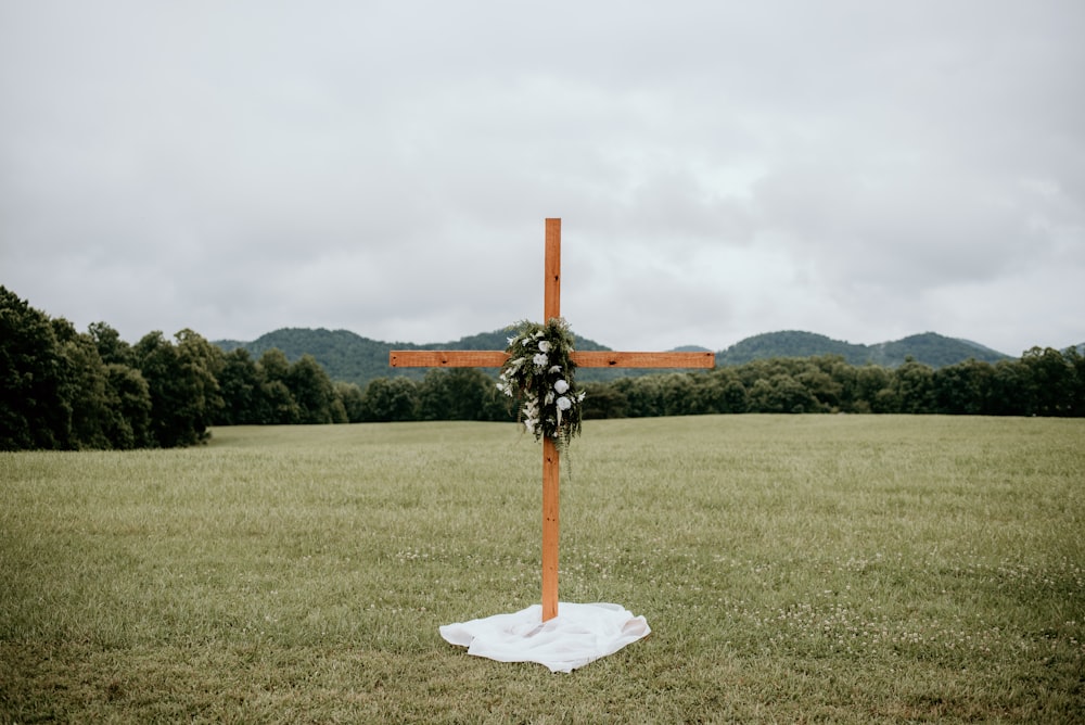 orange and white cross on green grass field under white clouds during daytime