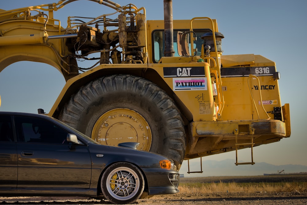 blue car parked beside yellow heavy equipment