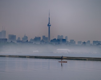 person riding on boat on water near city buildings during daytime