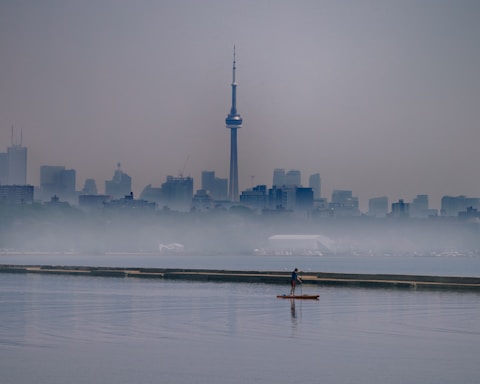 person riding on boat on water near city buildings during daytime