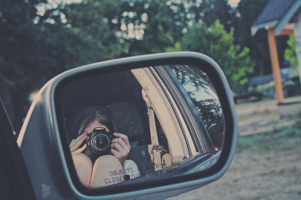 person taking photo of car side mirror